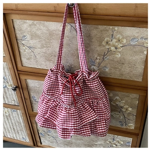 Detail view of red gingham tote bag featuring ruffle trim and drawstring closure