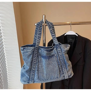 Detailed macro view of the sturdy washed blue denim fabric and reinforced stitching on tote bag