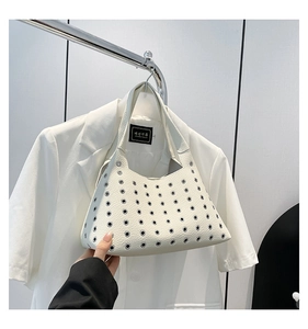 Detail of white leather shoulder bag with silver metal eyelets and minimalist rivet design