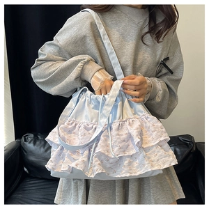 Detalle del bolso tote azul claro con volantes florales de varias capas y asa de lona