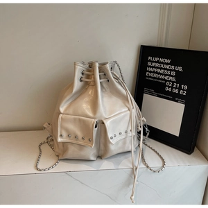 Detail of off-white bucket bag with silver rivet studs and chain strap on marble
