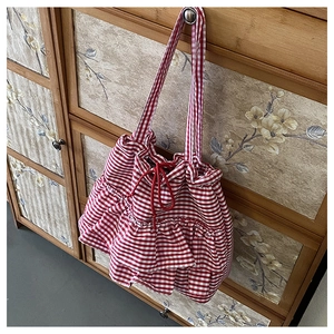 Detail of red gingham canvas tote bag featuring drawstring closure and ruffle accents