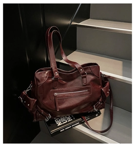 Close-up of vintage deep red tote bag featuring silver rivet studs and textured synthetic leather