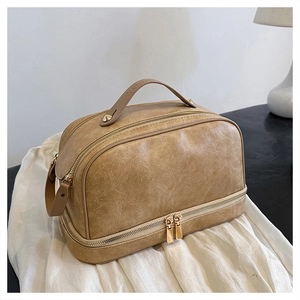 Close-up of khaki PU leather makeup bag featuring dual golden zippers and wide handle