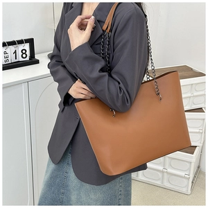 Detail of caramel brown tote bag showing matte leather texture and metal chain strap