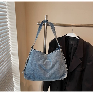 Vintage blue washed denim tote bag hanging on a metal rack with casual retro style
