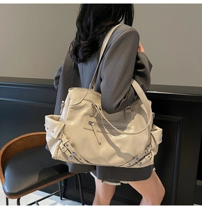 Close-up of beige motorcycle tote bag with silver studs and decorative straps details