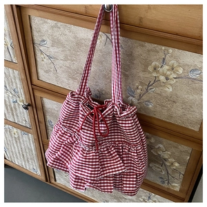 Close-up of red and white checkered canvas tote bag with ruffled edges and drawstrings