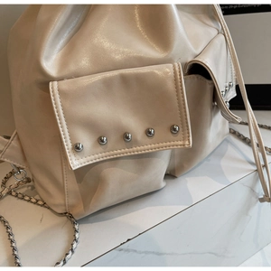Macro detail of beige glossy backpack showing silver rivets and high-quality PU leather