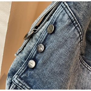 Close-up of vintage metal buttons and ring detail on a washed blue denim tote bag