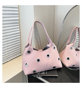 Detailed view of pink leather handbag with silver eyelets and twin slim handles