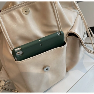 Detail showing the large capacity side pocket of the cream waterproof shoulder bag