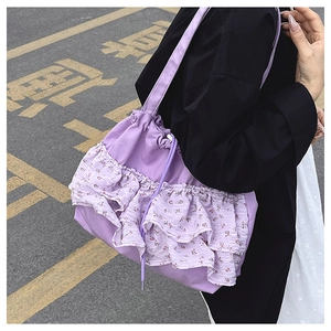 Detalle de bolso de lona morado con volantes de encaje floral y cierre de cordón
