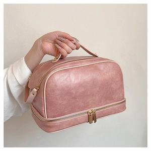 Detail view of the vintage pink PU leather makeup bag with dual gold zippers and sturdy handle