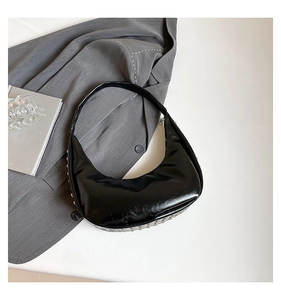 Detail der schwarzen Lackleder-Hobo-Tasche mit silbernen Metallösen und Glanzfinish