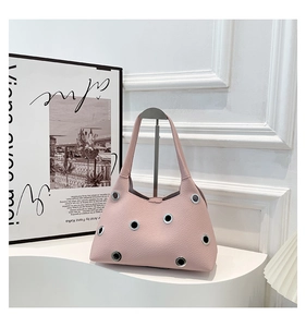 Detailed view of pale pink lychee leather handbag with silver eyelets and smooth texture
