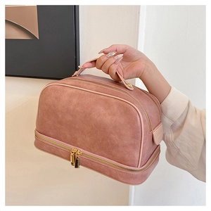 Detail of a large pink PU leather cosmetic bag with gold zippers held by a hand