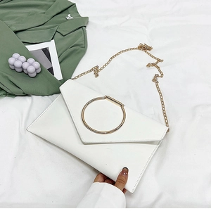 Détail de la pochette enveloppe blanche avec grand anneau doré et bandoulière chaîne