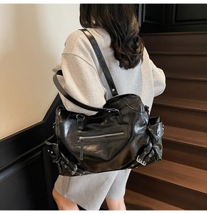 Close-up of black rivet tote bag with side pockets and industrial buckle details