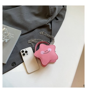 Detailed view of pink star shaped mini bag next to smartphone showing its compact size