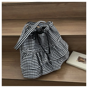 Detail of gingham canvas tote bag featuring layered ruffles and black drawstring closure
