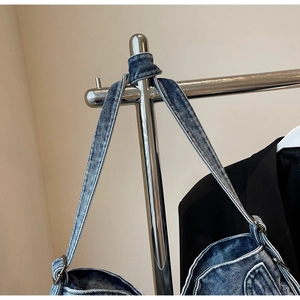 Detail of blue denim shoulder strap with silver metal buckle and vintage wash texture