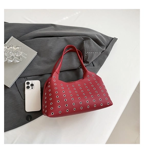 Macro view of red lychee grain leather handbag with stylish silver metal eyelet detailing