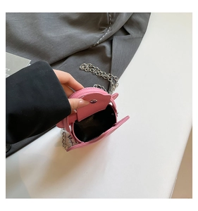 Detailed view of pink mini crossbody bag with litchi grain texture and silver chain