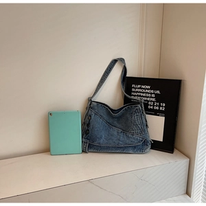 Detail of vintage blue denim tote bag with side metal buttons and diagonal stitching