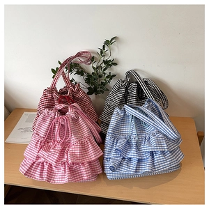 Detail of colorful gingham tote bags with ruffled edges and drawstring closure