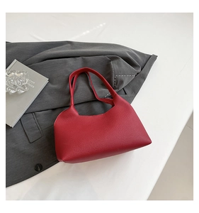 Detailed macro view of the vivid red lychee grain leather texture on the shoulder handbag