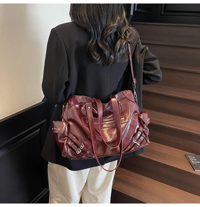 Detail of burgundy oversized tote bag featuring silver hardware rivets and glossy leather finish