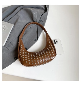 Detailansicht der Metallnieten an einer braunen Hobo-Tasche neben Alltags-Accessoires