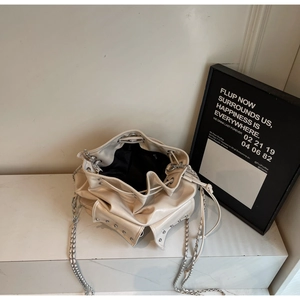 Detail of cream bucket bag showing silver studs, chain strap and black lining interior