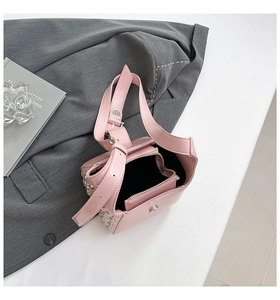 Détail du sac seau rose montrant les rivets argentés latéraux et la bandoulière large