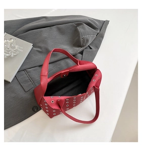 Detail of red eyelet shoulder bag with silver rivets and textured leather finish