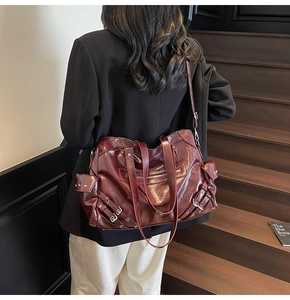 Detail of burgundy large tote bag showing metal buckles and biker style pockets