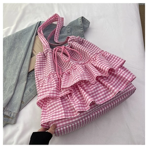 Detail shot of a floral plaid tote bag with pink drawstring and ruffled edges on white linen