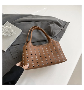 Close-up of brown pebbled leather texture with silver rivet detailing on underarm bag
