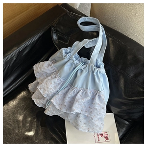 Detalle del bolso tote azul claro con volantes florales y cierre de cordón en tela suave