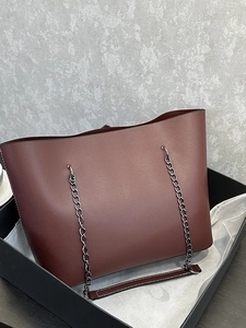 Minimalist burgundy leather tote bag with metallic chain handles in a gift box