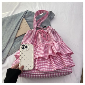 Detailed top view of pink checkered tote bag with ruffle trim and drawstring on white cloth