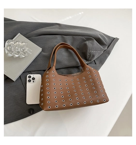Detailed view of brown lychee leather texture and silver metal eyelets on a handbag