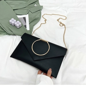 Détail de la pochette enveloppe noire avec boucle dorée et bandoulière en chaîne