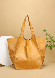 Detail view of ginger yellow tote bag with large outer pocket and grained texture leather