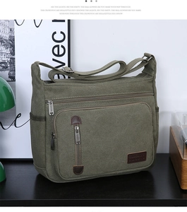 Close-up of olive green canvas messenger bag with leather zipper pulls and pockets