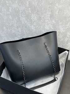 Minimalist black leather tote bag with chain strap presented in a luxury black gift box