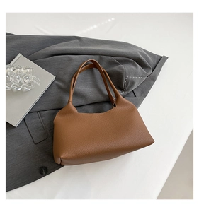 Detailed texture of brown pebble leather underarm bag on professional suit backdrop