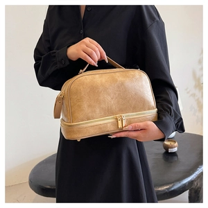 Detail of vintage tan leather makeup bag showing dual zipper and metal studs