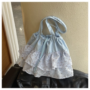 Detalle del bolso tote azul claro con tres capas de volantes de gasa floral y cordón ajustable